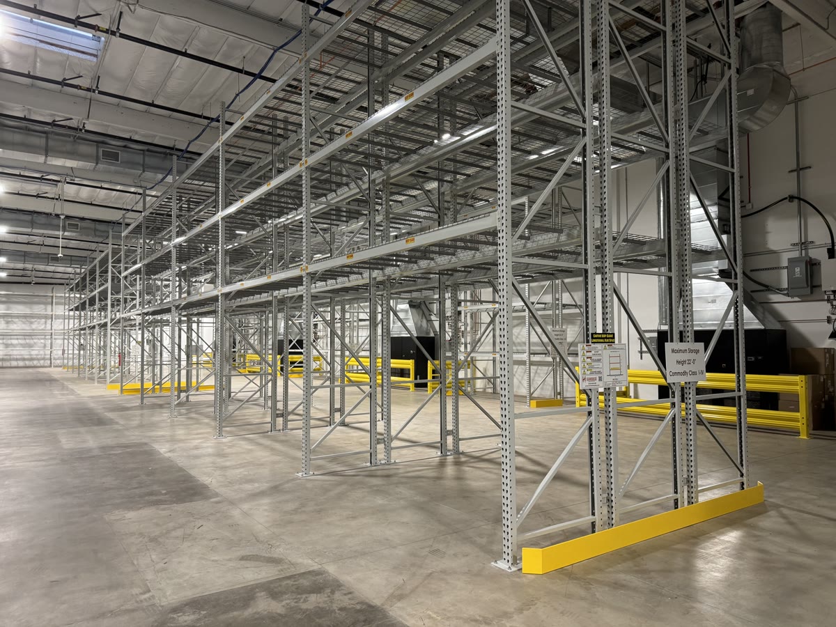 Angled view of galvanized selective rack rows with location labels and yellow end-of-row guards